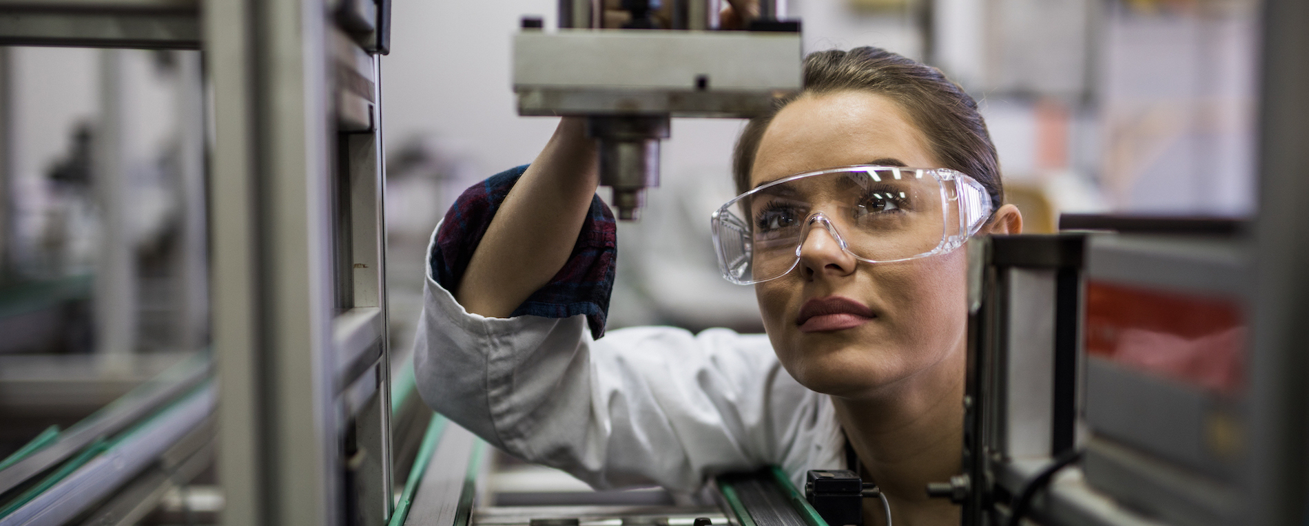 Female engineer examining machine part on a production line.