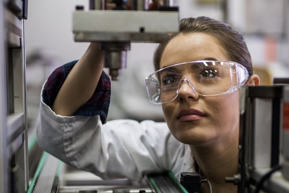 Quality control inspector working on a manufacturing machine in laboratory.