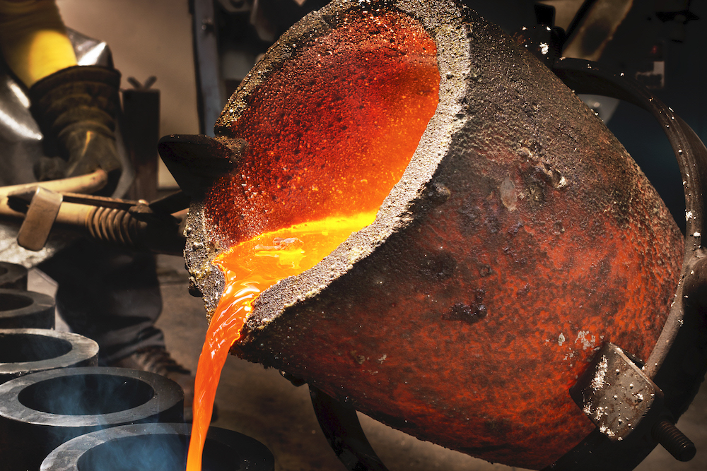 Worker pouring liquid metal into crucible.