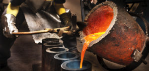 Worker pouring liquid metal into crucible.